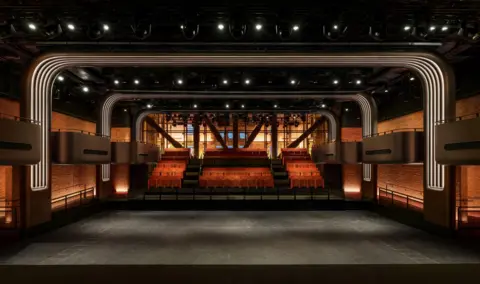 Apple Music Inside Apple Music's new music venue in London. The photo shows tiered seating and staggered boxes for an elevated view of the stage. The back wall is made of glass and offers views of an entry lobby and the Thames